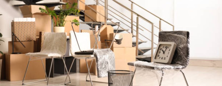 Cardboard boxes with packed stuff near stairs in office. Moving day