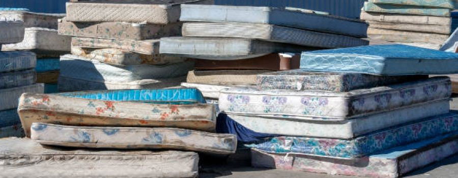Dirty used mattresses piled at recycling site.